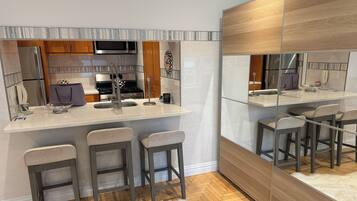 A modern kitchen with a central island, bar stools, and a large mirror.