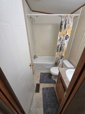 A compact bathroom with a shower, toilet, and sink.