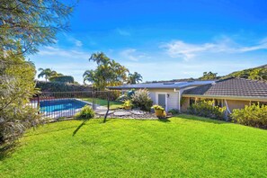 Ein Wohnhaus mit Schwimmbad, überdachter Terrasse und gepflegtem Rasen.