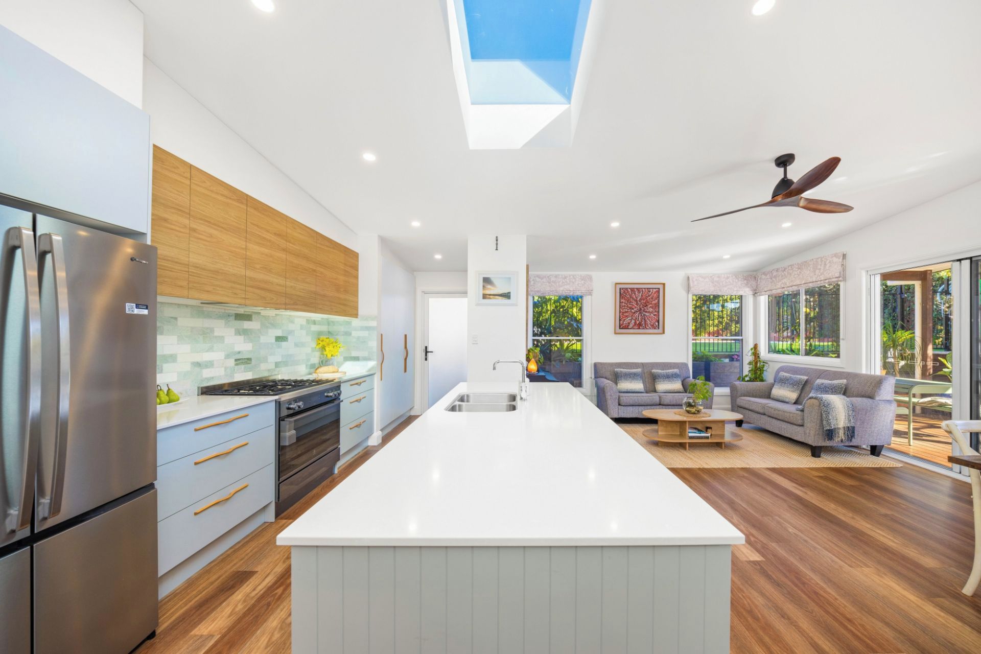 A modern kitchen with a central island, wooden cabinets, and a built-in oven.