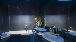 A modern bathroom with a skylight, a bathtub, two sinks, and a large mirror. - The Architect's House (Santorini)