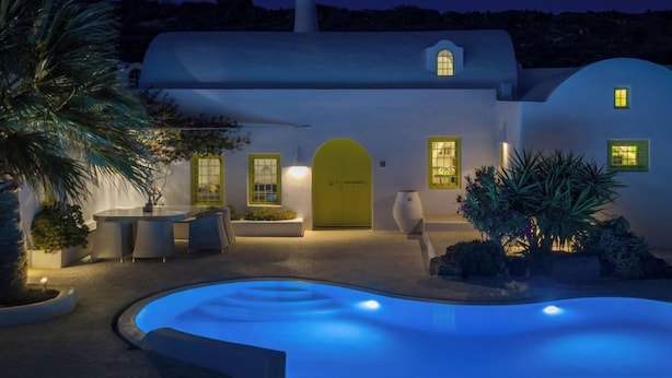 A modern villa with a swimming pool, outdoor seating, and a well-lit entrance. - The Architect's House (Santorini)