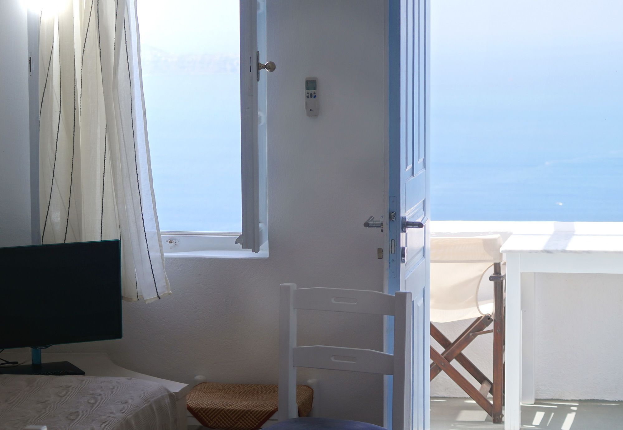 A room with a bed, a chair, a television, a window, and a view of the sea.