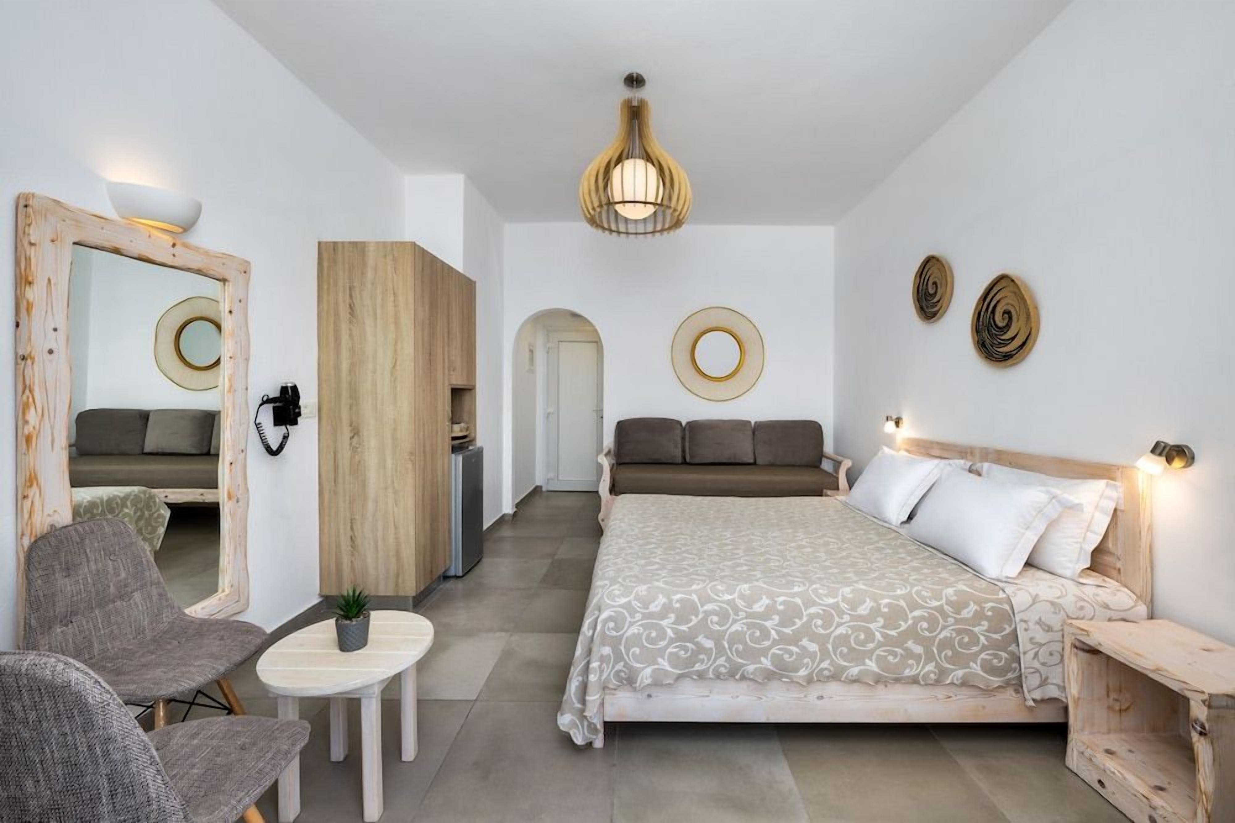 Une chambre à coucher avec un lit, deux chaises, une petite table, un miroir et une armoire.
