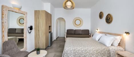 A bedroom with a bed, two chairs, a small table, a mirror, and a wardrobe.
