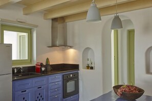 Una cocina con horno empotrado, un lavamanos y una ventana. Hay un cuenco con fruta sobre la encimera.