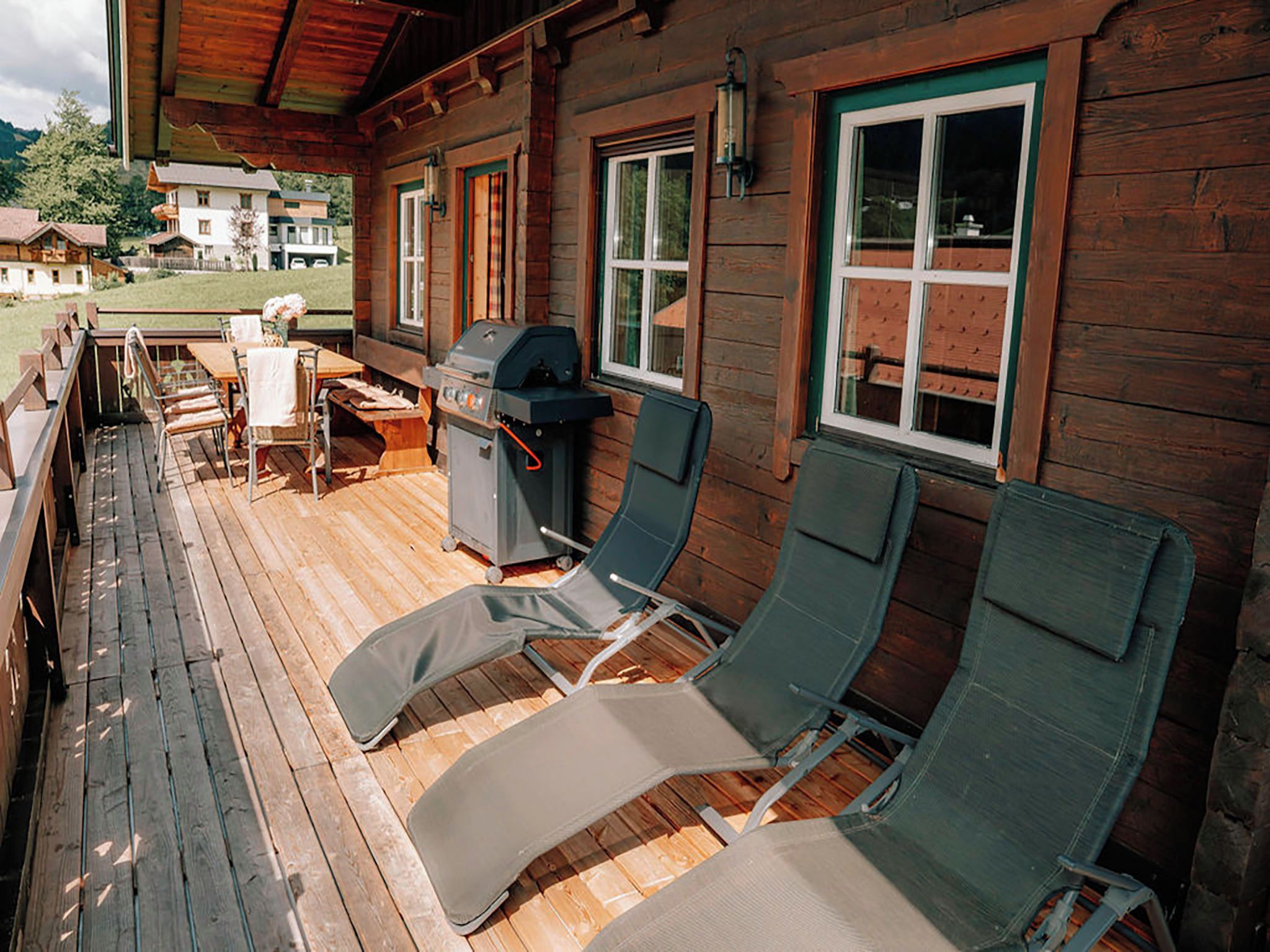 A wooden deck with outdoor seating and a barbecue grill.