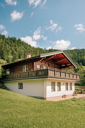 Eine traditionelle Chalet mit Holzbalkon, eingebettet in einen bewaldeten Hang.