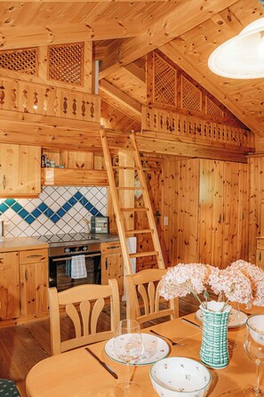 A wooden interior with a kitchen, dining area, and a ladder. - Zirbenhütte by Interhome (Forstau)