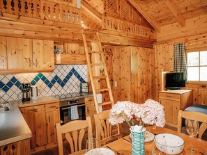 A wooden cabin interior with a kitchen, dining area, and a TV. - Zirbenhütte by Interhome (Forstau)
