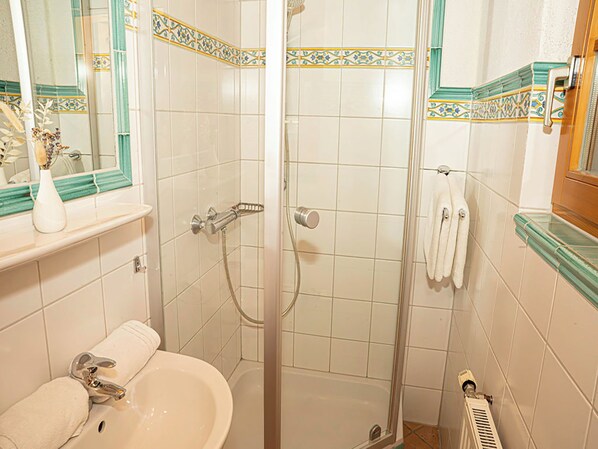 A bathroom with a shower, sink, and towel rack.
