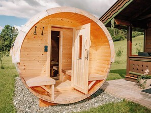 A wooden cabin with a circular exterior, a door, a bench, and a small table. - Zirbenhütte by Interhome (Forstau)