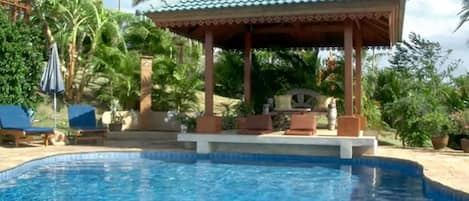 A swimming pool with lounge chairs and a gazebo.