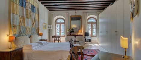 Habitación de hotel con cama, escritorio, silla, televisión y ventana grande con vistas.
