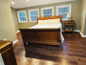 Quarto com cama de madeira, mesa de cabeceira e janela com persianas.