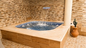 A hot tub with a blue mosaic edge, surrounded by a wooden and stone tiled floor, and a cactus in a terracotta pot. - Vrbo Property (Santo Domingo Este)
