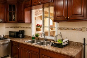 A kitchen with granite countertops, stainless steel appliances, and wooden cabinets. - Vrbo Property (Santo Domingo Este)