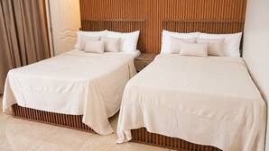 Habitació d'hotel amb dos llits, ambres de fusta i una cortina a l'esquerra.