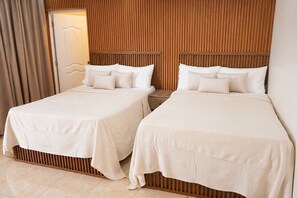 Ein Hotelzimmer mit zwei Betten, Holz Kopfteilen und einem Vorhang auf der linken Seite.