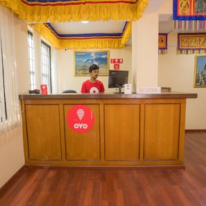 A reception desk with a wooden finish, a red OYO logo, and a reception sign. - Lost Garden Apartment & Guest House (Kathmandu)