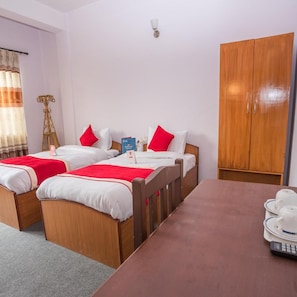 A hotel room with two beds, a wooden wardrobe, a table with tea set, and a lamp. - Lost Garden Apartment & Guest House (Kathmandu)