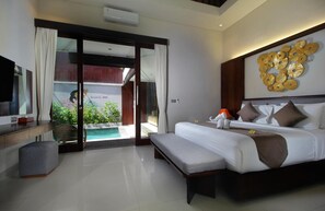 Habitació d'hotel moderna amb un llit gran, una banca, una televisió, un escriptori i vista a una piscina i vegetació.