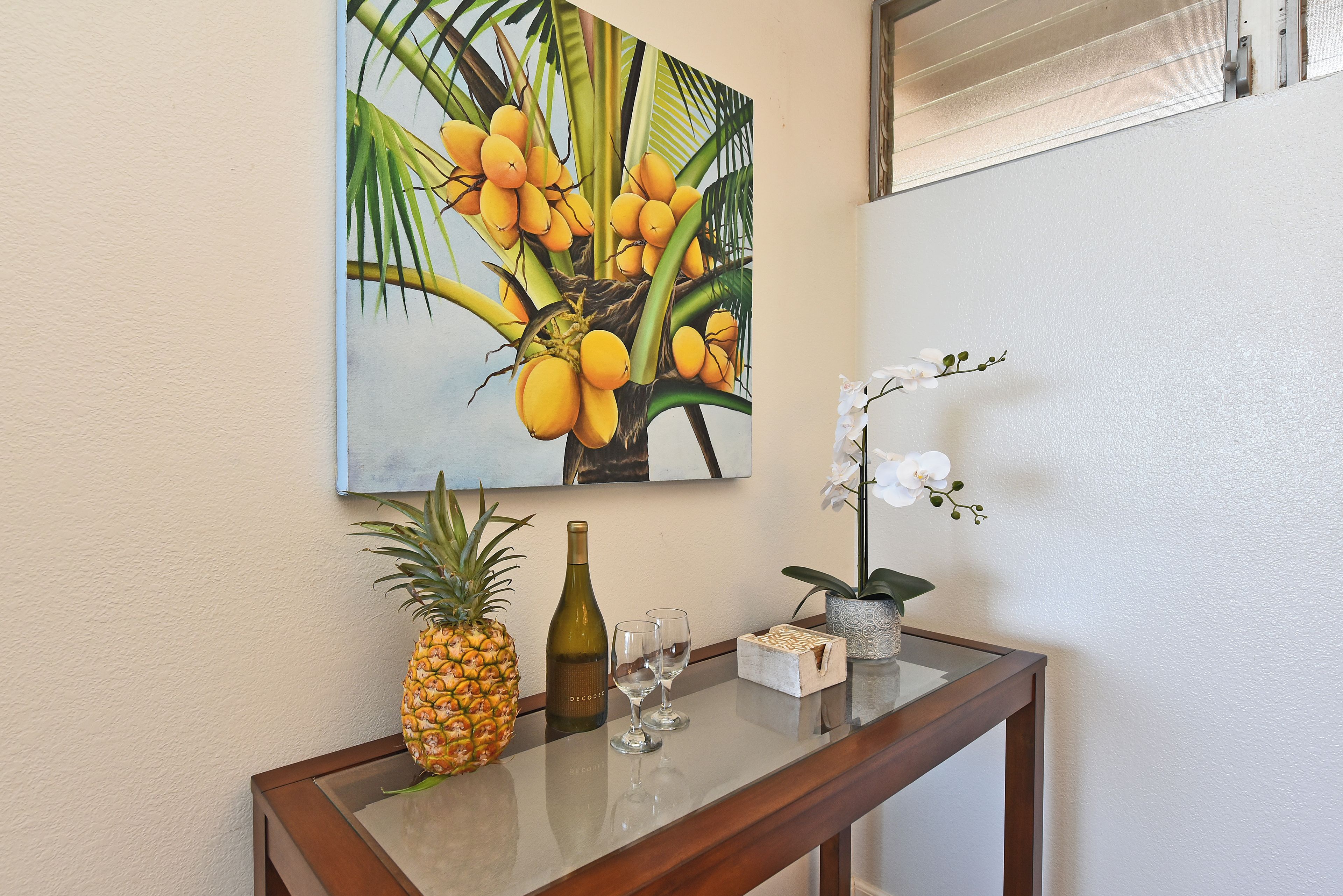 A glass-top table with a pineapple, a bottle, and a small orchid.