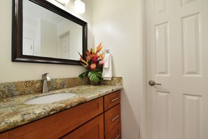 Une salle de bain avec un comptoir en granit, un lavabo, un miroir, une serviette et une porte.