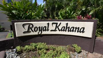 A sign with the name 'Royal Kahuna' in a stylized font, surrounded by lush greenery and a stone pathway.