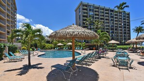 A hotel pool area with lounge chairs, umbrellas, and a large building in the background. - Oceanfront - Luxury View - 2 Beds (Lahaina)