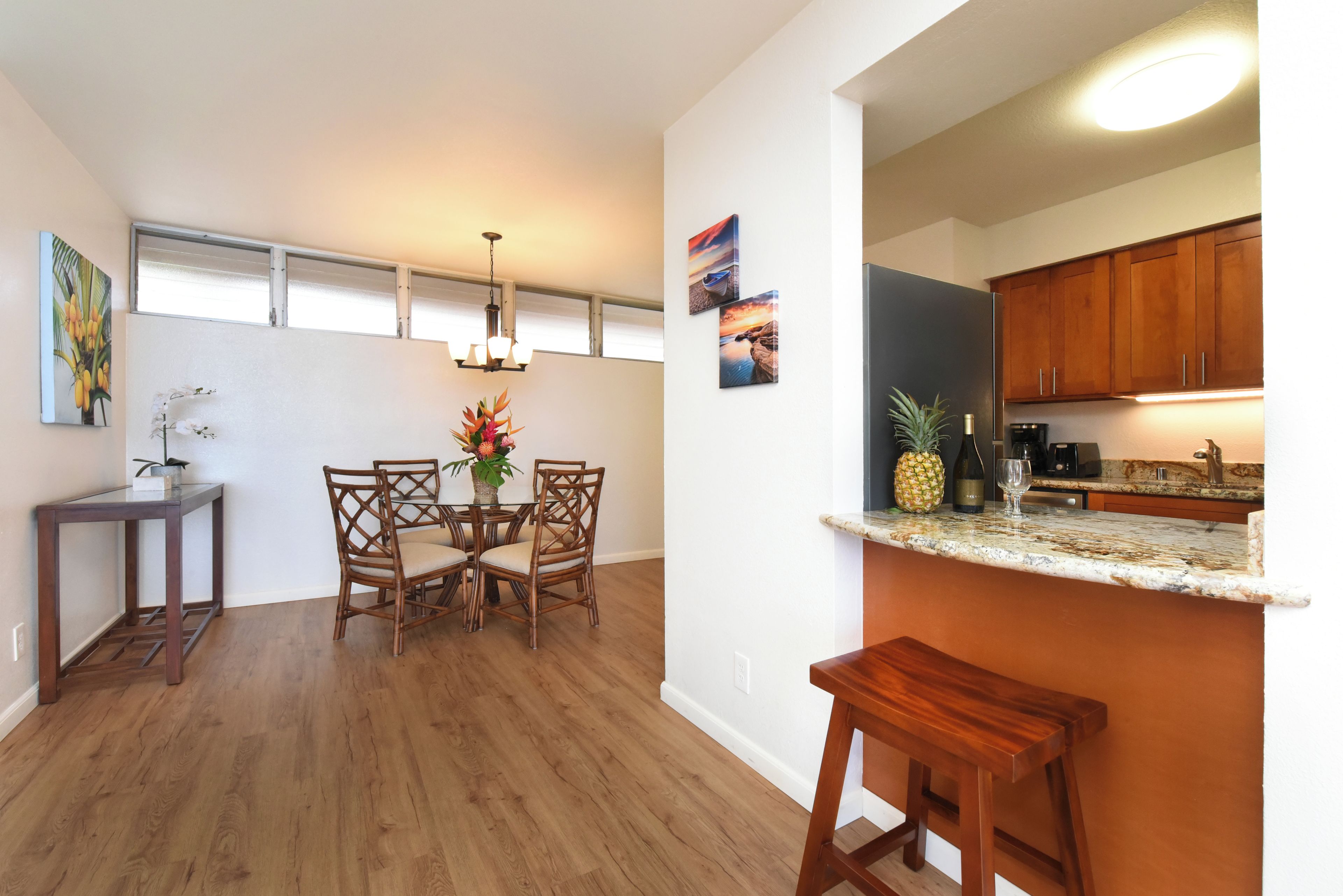 A modern kitchen with wooden cabinets, a dining area with a table and chairs, and a small bar area with a countertop.