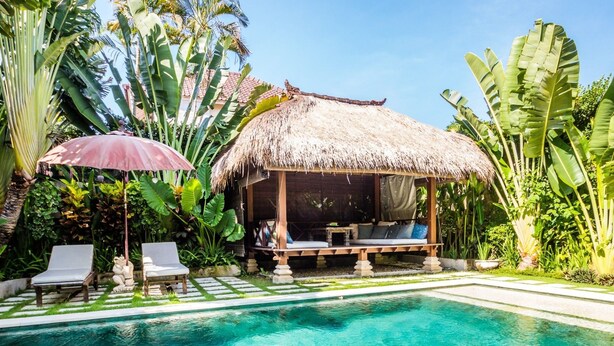 A pool with a thatched-roof structure and lounge chairs. - Villa Gembira (Keroboken Kelod)