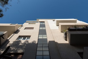 Un edifici modern amb un passadís central de vidre, diverses finestres i un terrat pla.