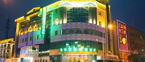 A multi-story hotel with a prominent sign at the top and multiple illuminated windows.