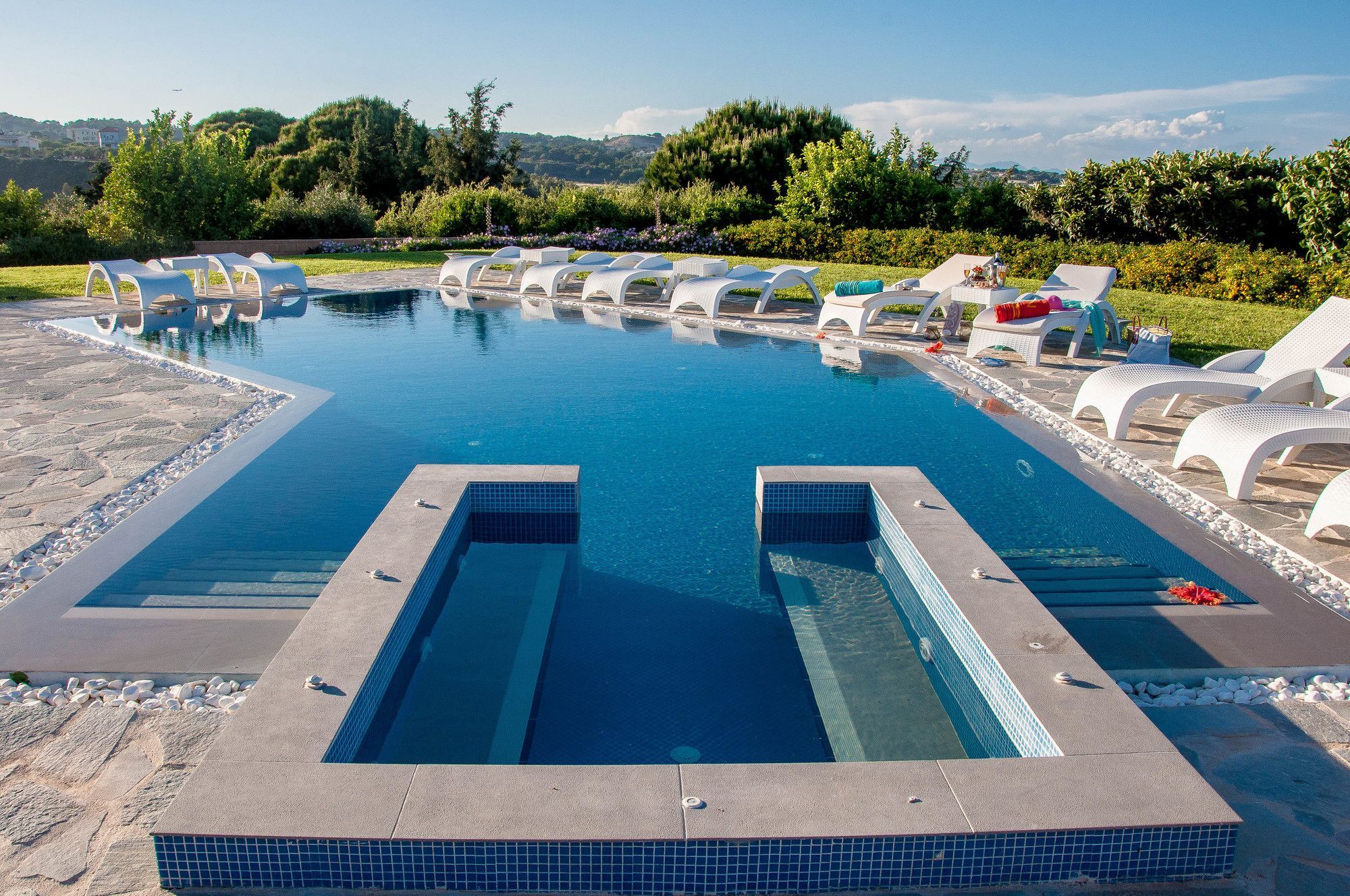 Una piscina con sillones de descanso y vistas del paisaje circundante.