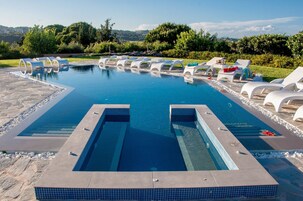 Una piscina con sillones de descanso y vistas del paisaje circundante.