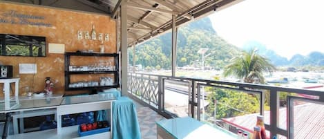 A restaurant with a view of mountains, a counter with condiments, and a tiled floor.