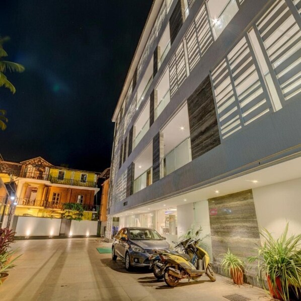 A multi-story building with a modern facade, a car, and a motorcycle parked in front.