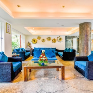 A modern living room with blue sofas, a glass coffee table, and decorative sunflowers on the wall.