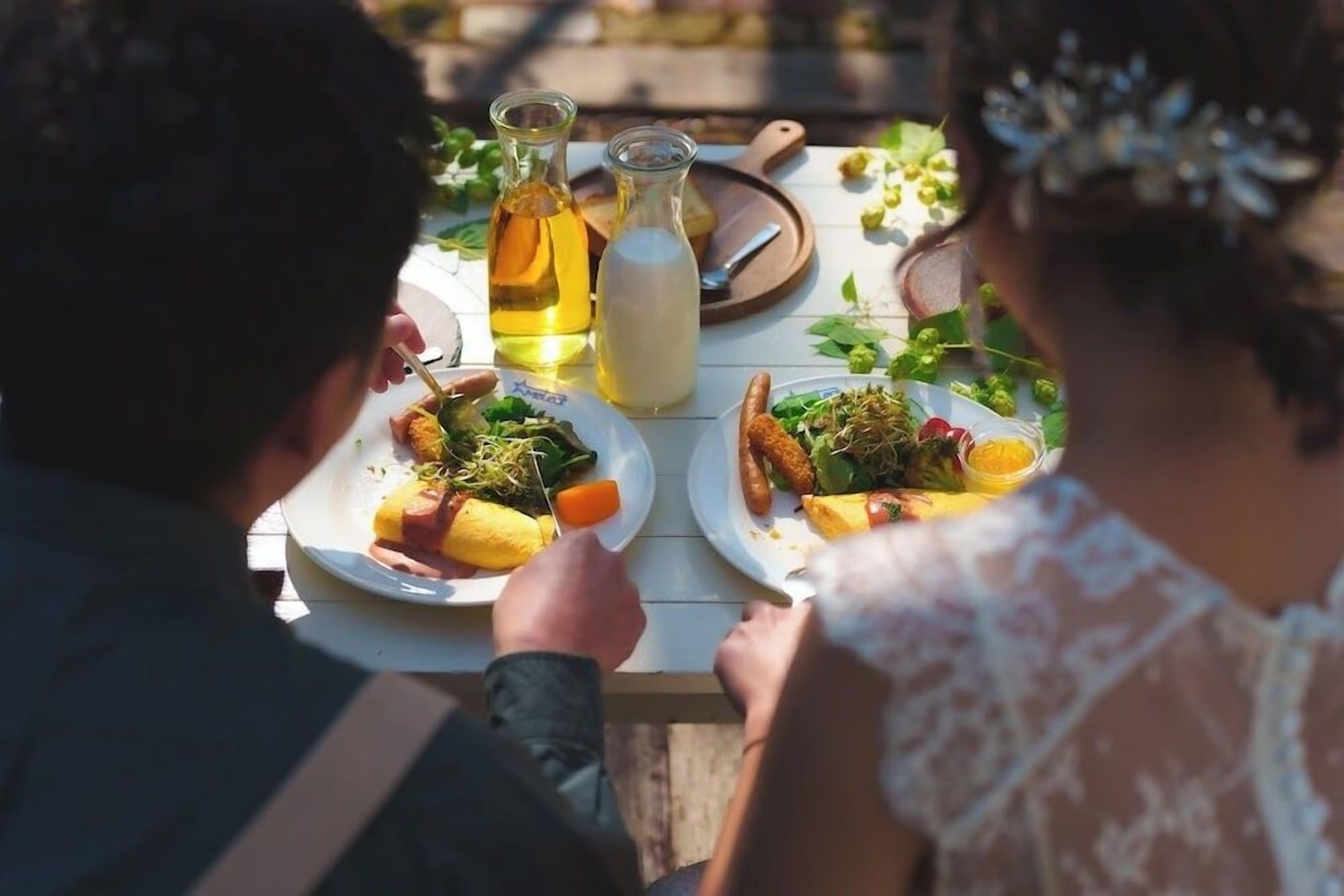 A dining table with plates of food, a bottle of oil, and a jug of milk.