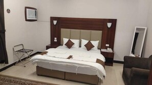 A hotel room with a large bed, a bedside table, a chair, a mirror, and an air conditioning unit. - Al Eairy Furnished Apartments Al Madinah 9 (Madinah)