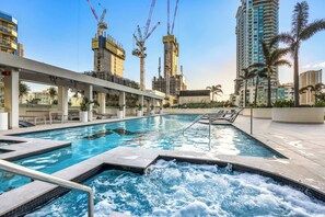A swimming pool with a hot tub, lounge chairs, and a view of surrounding high-rise buildings. - The Mojo Ocean Suite Sixty-Sixth Floor, Meriton (Surfers Paradise)