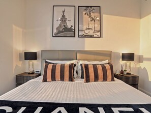A hotel room with a bed, two nightstands, two wall-mounted lamps, and two framed pictures. - The Mojo Ocean Suite Sixty-Sixth Floor, Meriton (Surfers Paradise)