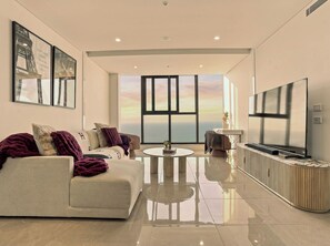 A modern living room with a sofa, coffee table, and a large TV. - The Mojo Ocean Suite Sixty-Sixth Floor, Meriton (Surfers Paradise)