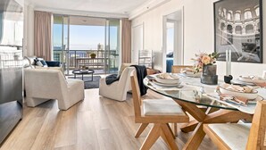 Una sala moderna con una mesa de comedor de vidrio, asientos cómodos y un balcón con vistas a la ciudad.