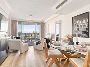 Ein modernes Wohnzimmer mit einem Glastisch, gemütlicher Sitzgelegenheit und einem Balkon mit Stadtblick.