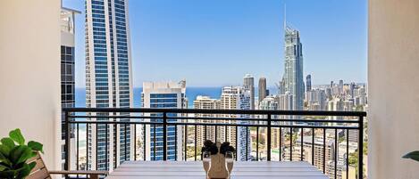 A balcony with a view of a city skyline and the ocean.