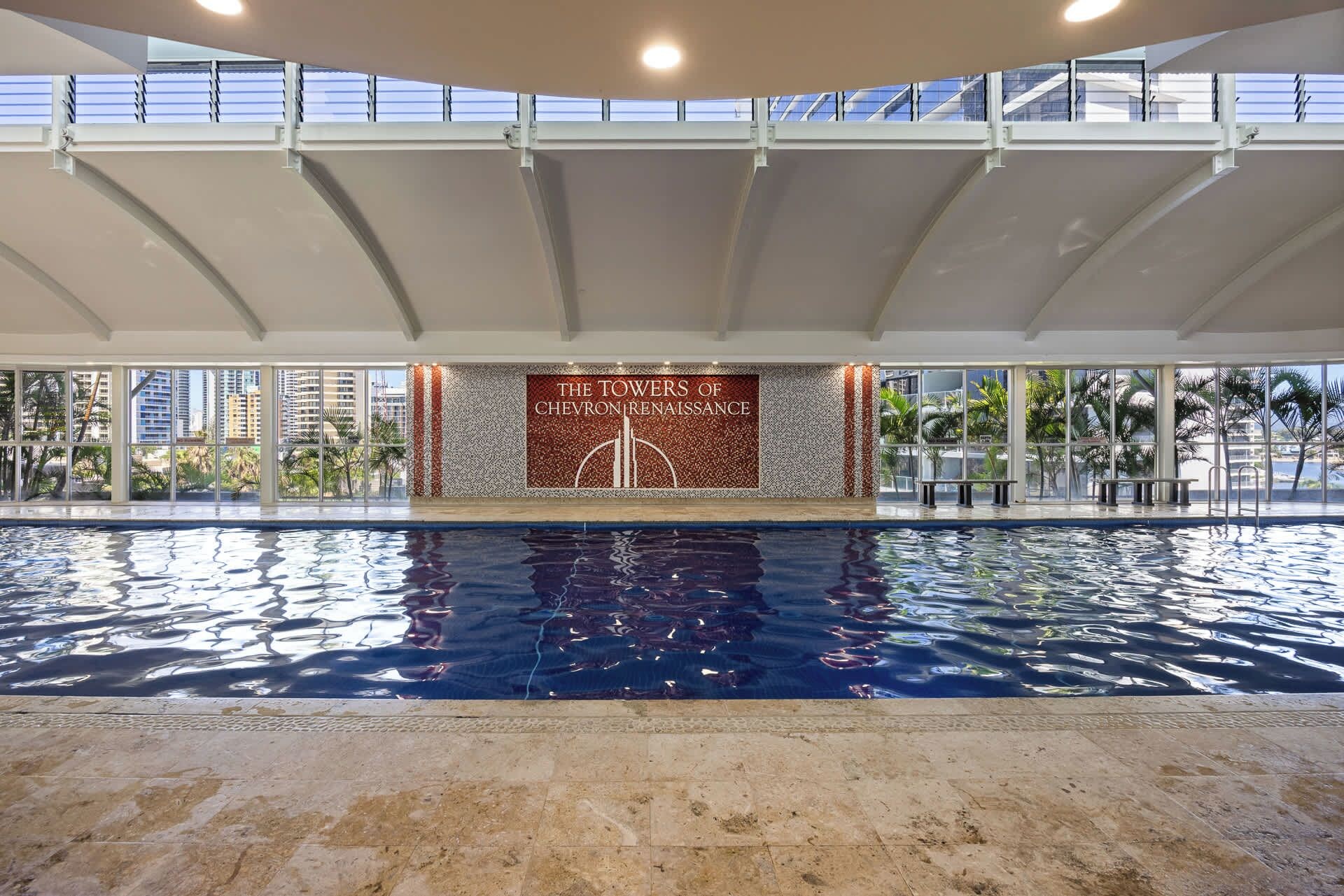 A swimming pool with a view of the cityscape, a sign reading 'The Towers of Chevrolet Renaissance,' and a covered area with a railing.