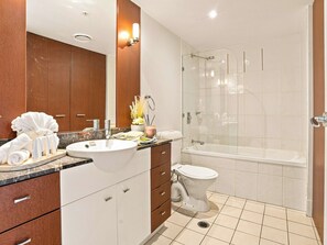 Ein modernes Badezimmer mit Waschbecken, Spiegel, Toilette und einer Duschkabine.