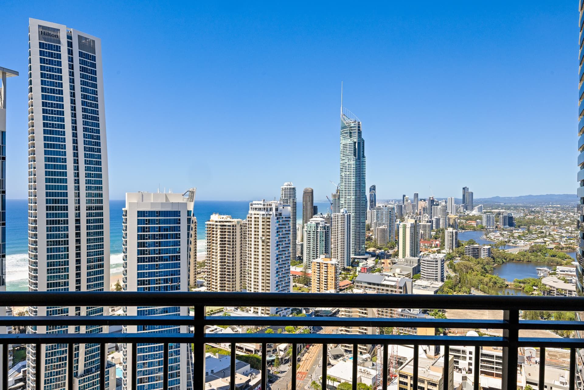 Une vue urbaine avec de hauts immeubles, dont un gratte-ciel remarquable à l’architecture originale, et une étendue d’eau en arrière-plan.